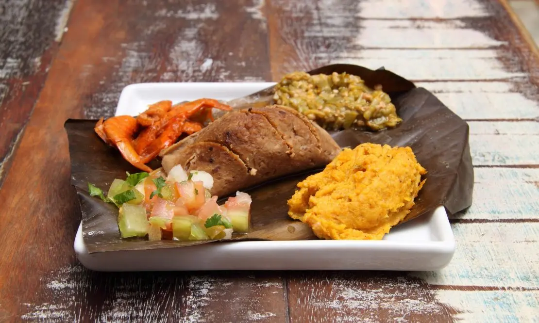 Prato de abará com alguns acompanhamentos, sobre uma superfície de madeira