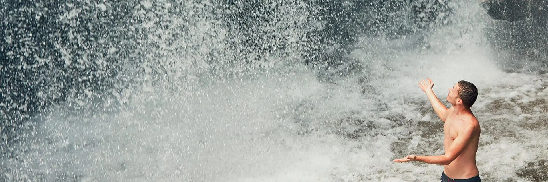 Imagem de um homem embaixo de uma cachoeira