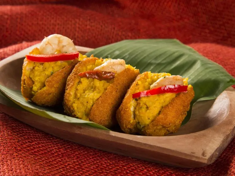 Prato de madeira com três acarajés um ao lado do outro