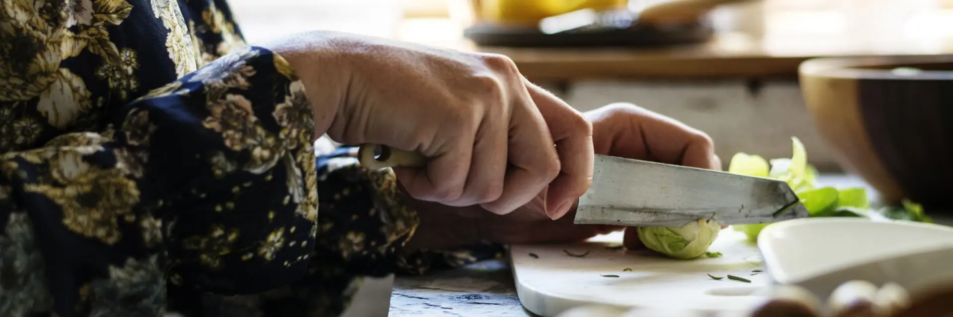 Imagem das mãos de uma pessoa segurando uma faca e cortando ingredientes para aprender como fazer acarajé