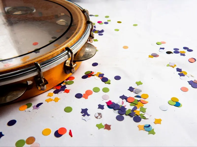 Pandeiro sobre uma mesa branca com confetes coloridos espalhados