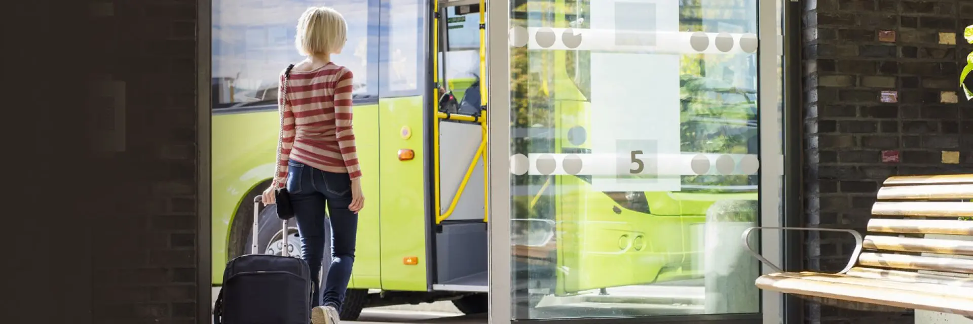 Imagem de uma mulher segurando uma mala e embarcando no onibus