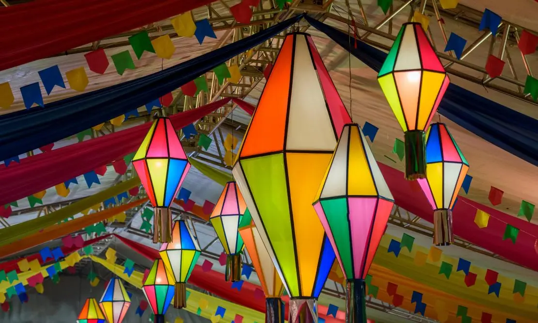 Balões e bandeirinhas coloridas de festa junina, ficadas no teto de um salão