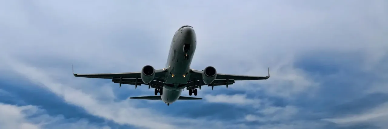 Imagem de um avião num céu azul com nuvens