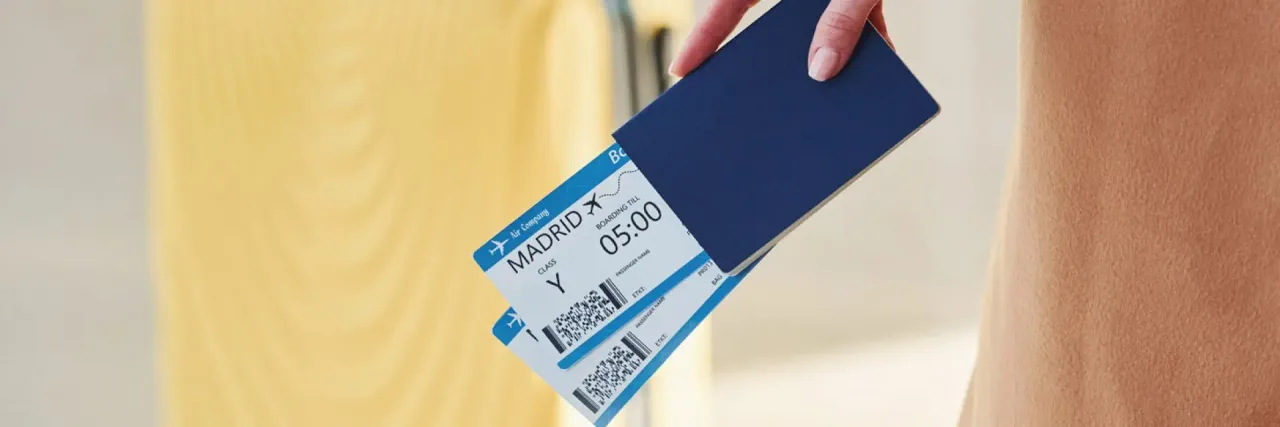 Imagem de uma mão segurando duas passagens de avião