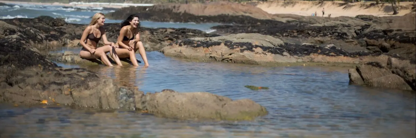 Imagem de duas mulheres se divertindo numa piscina natural