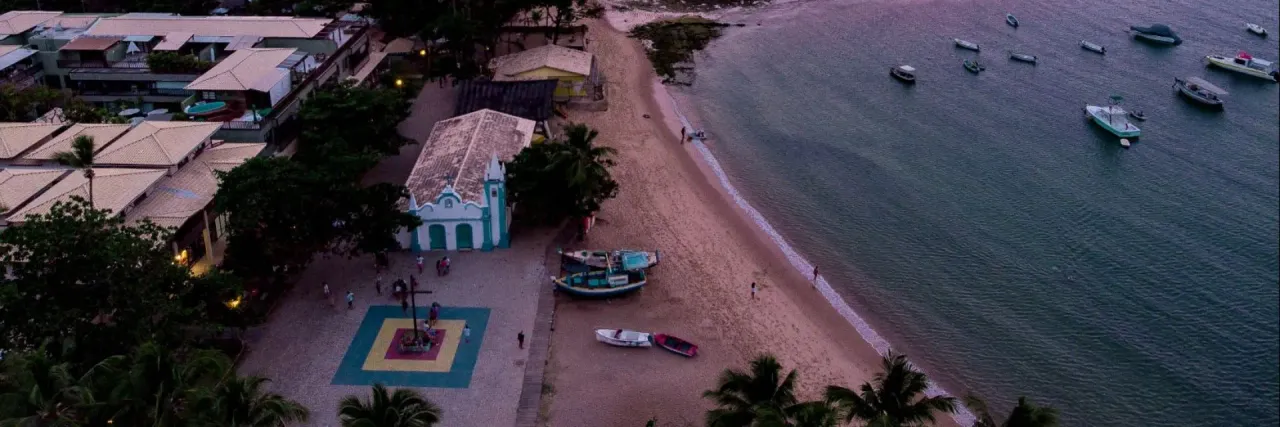 Imagem de uma praia com barcos na orla e no mar