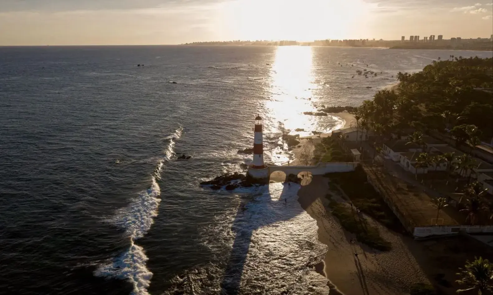 Pôr do sol com o farol no mar de Salvador, na região de Itapuã