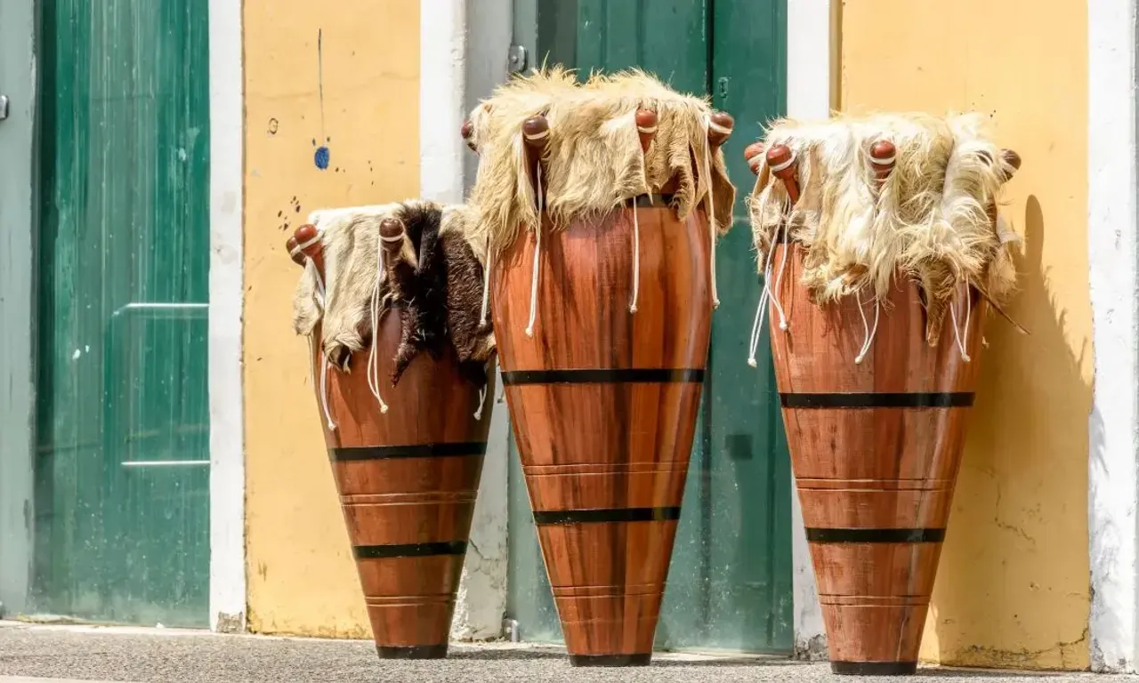 três atabaques do afoxé encostados em uma parede amarela com portas verdes