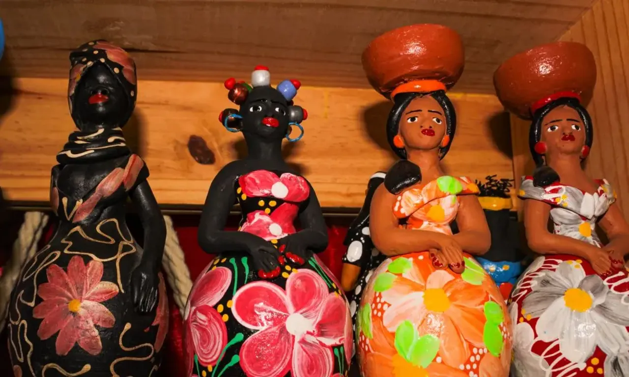 bonecas artesanais em cerâmica produzidas na Bahia, expostas em uma prateleira de madeira