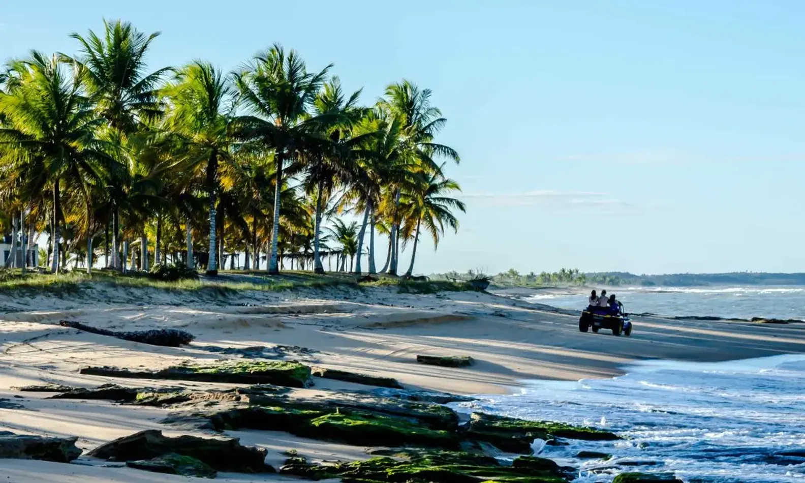 Buggy com algumas pessoas passeando pela orla de uma praia na Bahia
