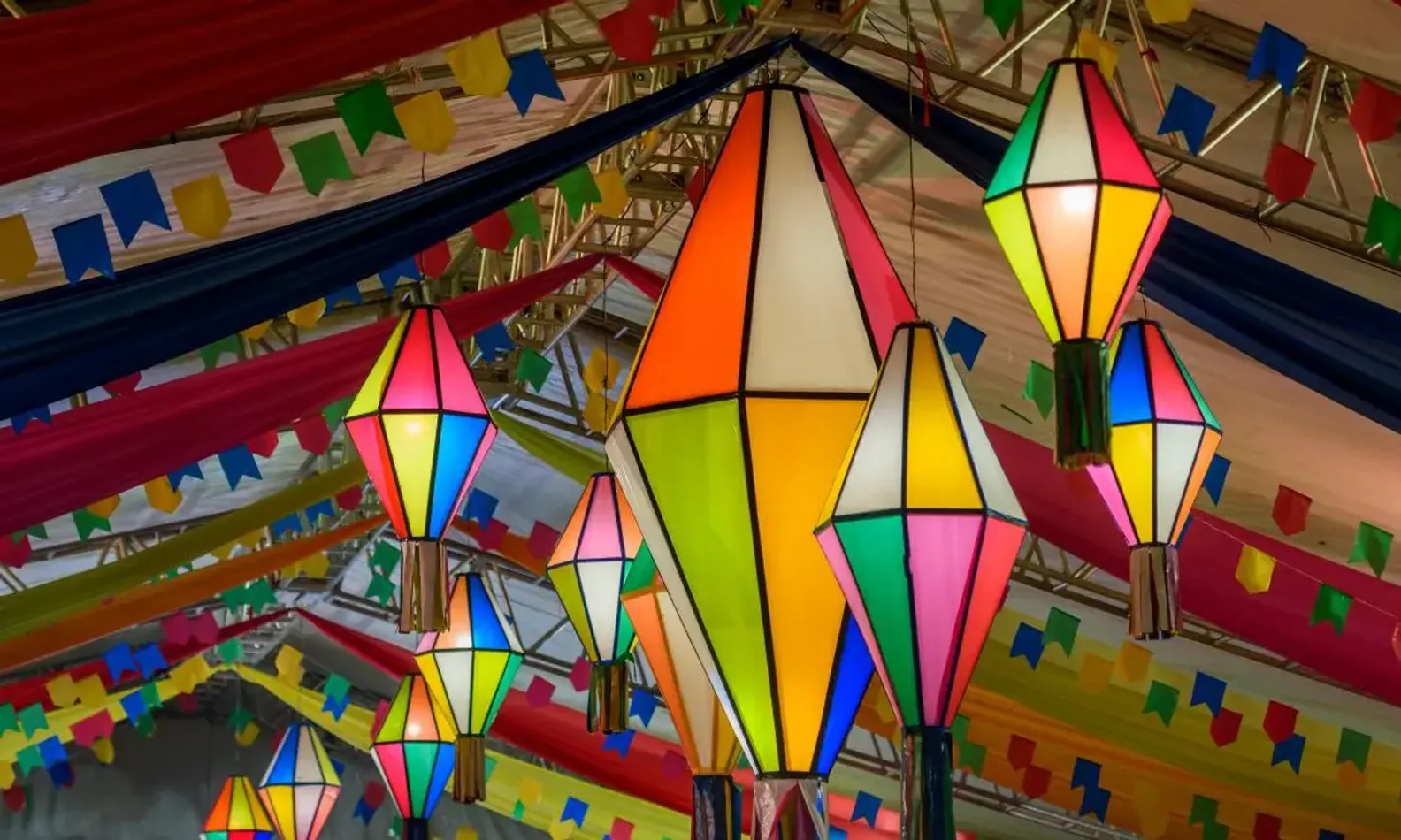 Balões e bandeirinhas coloridas de festa junina, ficadas no teto de um salão
